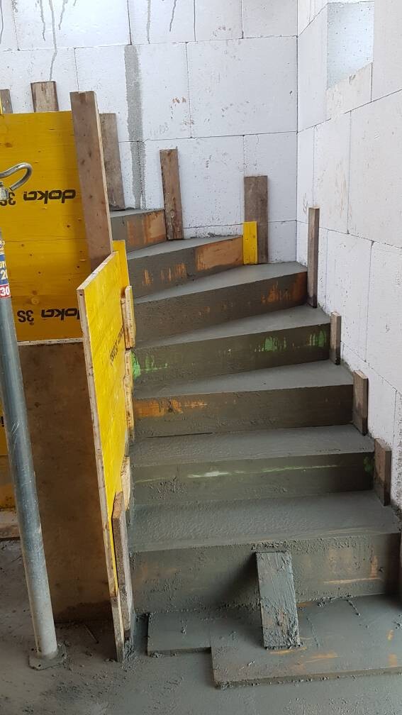 Betontreppe im Rohbau mit gelber Schalung und Bauholzstützen.