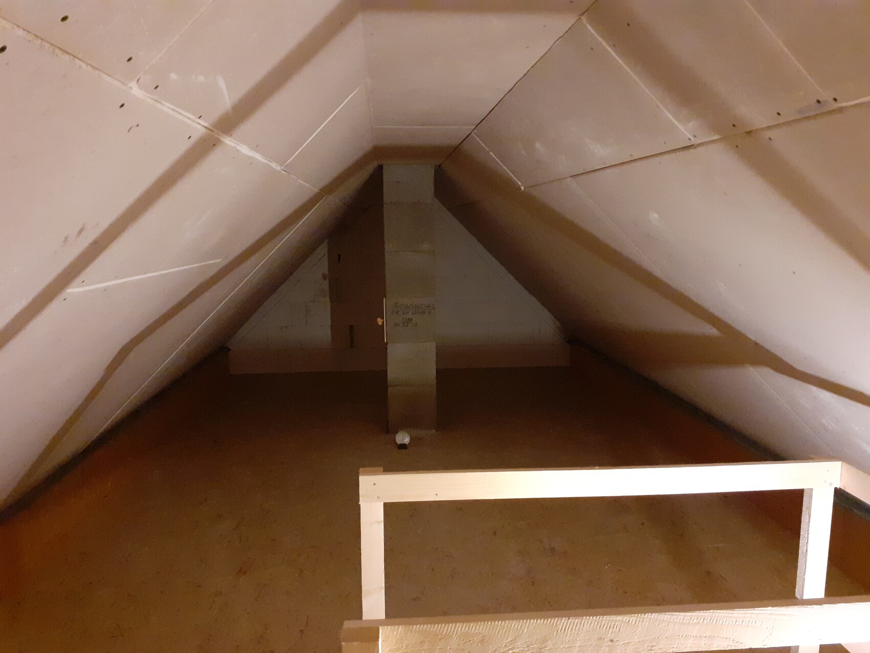 Dachboden mit spitzem Giebel, Holzboden, zentrale Stütze und vorderem Geländer.
