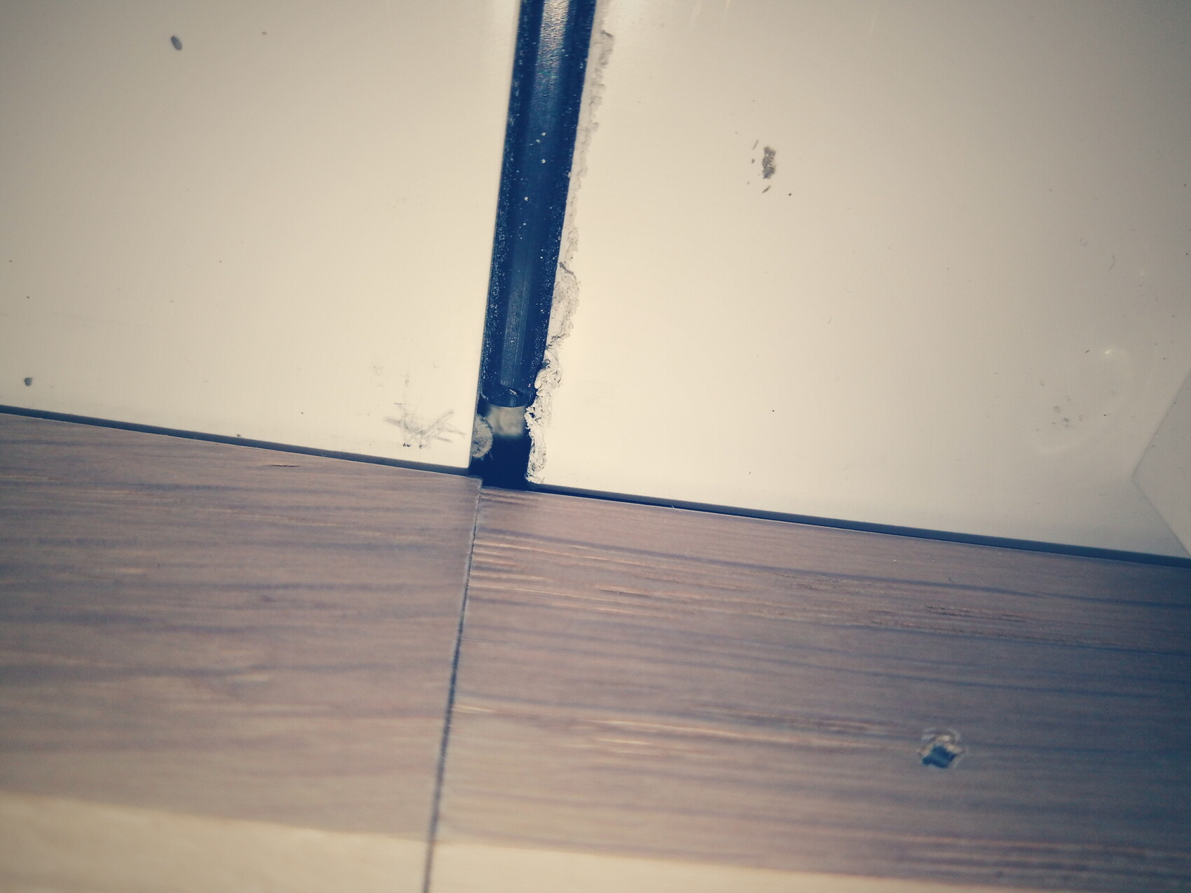 Unfertiger Innenausbau: Spalt Boden-Wand, Holzoptik, weiße Wand, blaue Leiste