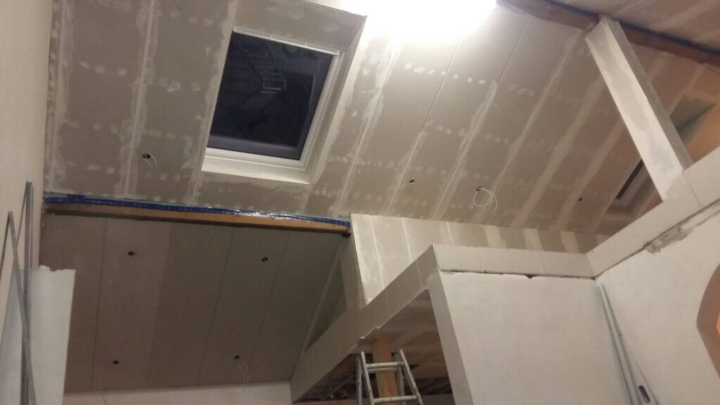 Raum im Ausbau mit Trockenbau-Decke, Dachfenster und Leiter im Vordergrund.