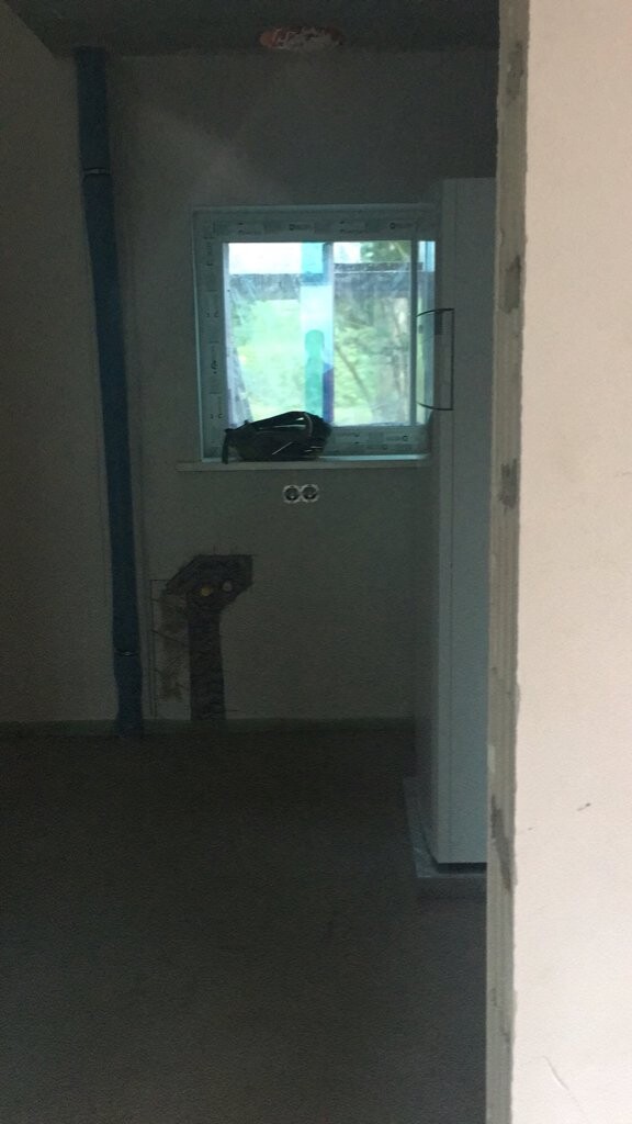 Unfertiger Innenraum mit Fenster, sichtbar Haustechnikrohre und Rohbauarbeiten