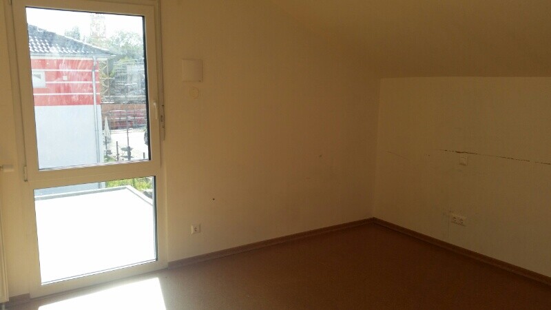Unfertiger Innenraum mit Tür zum Balkon, unmöbliert, Wandmarkierungen sichtbar.