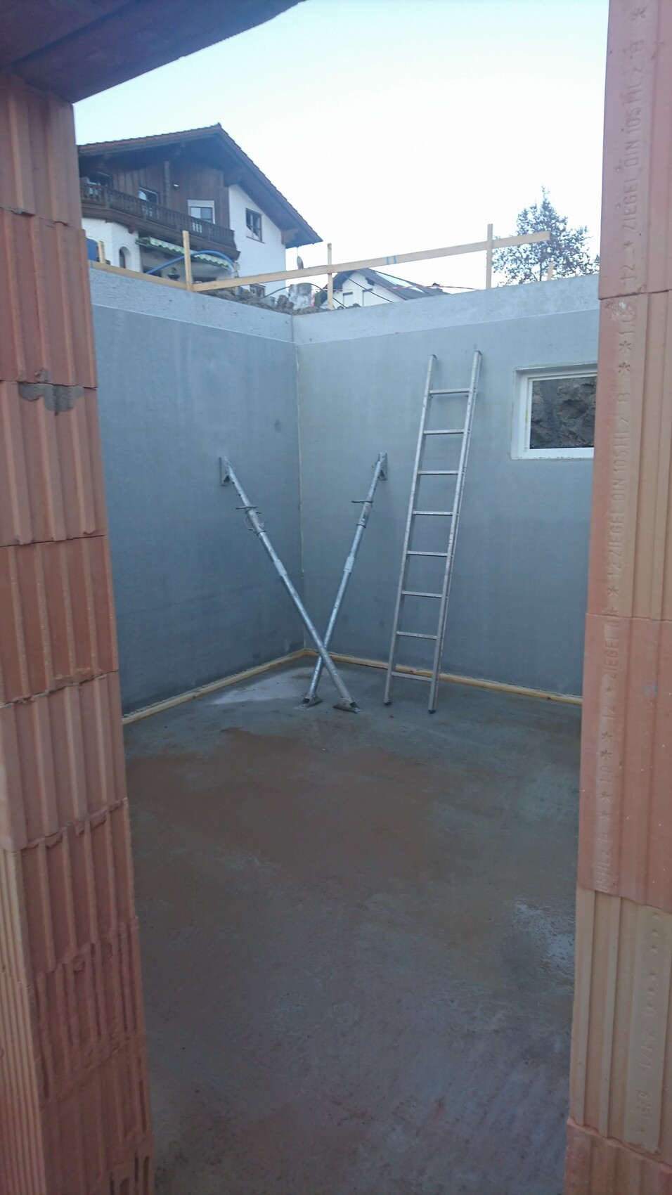 Baustelle: Innenraum aus Beton mit Leiter, zwei gekreuzten Stützbögen und kleinem Fenster.