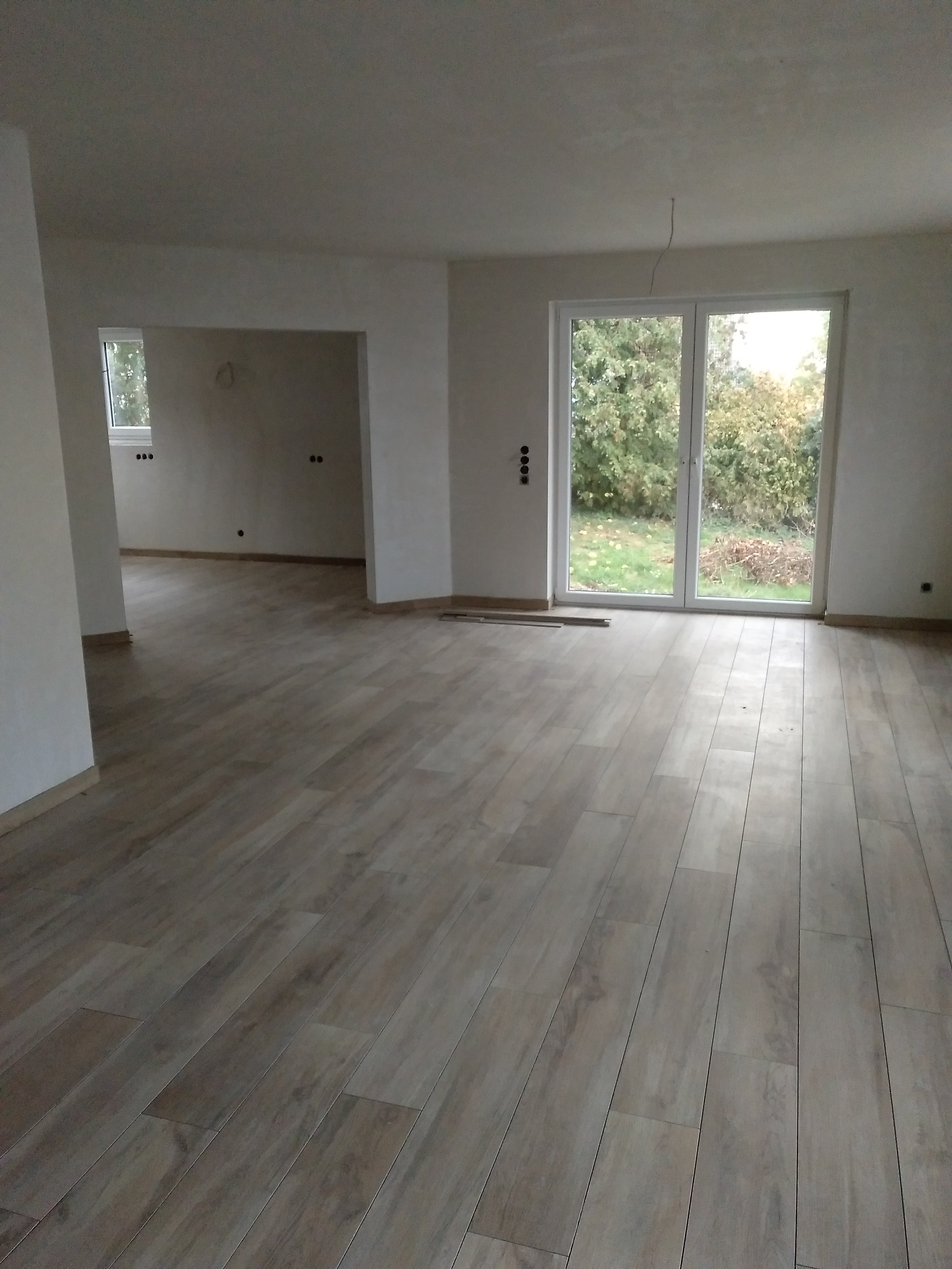 unfertiger-wohnraum-mit-parkettboden-und-grosser-glas-tuer-zum-garten.jpg