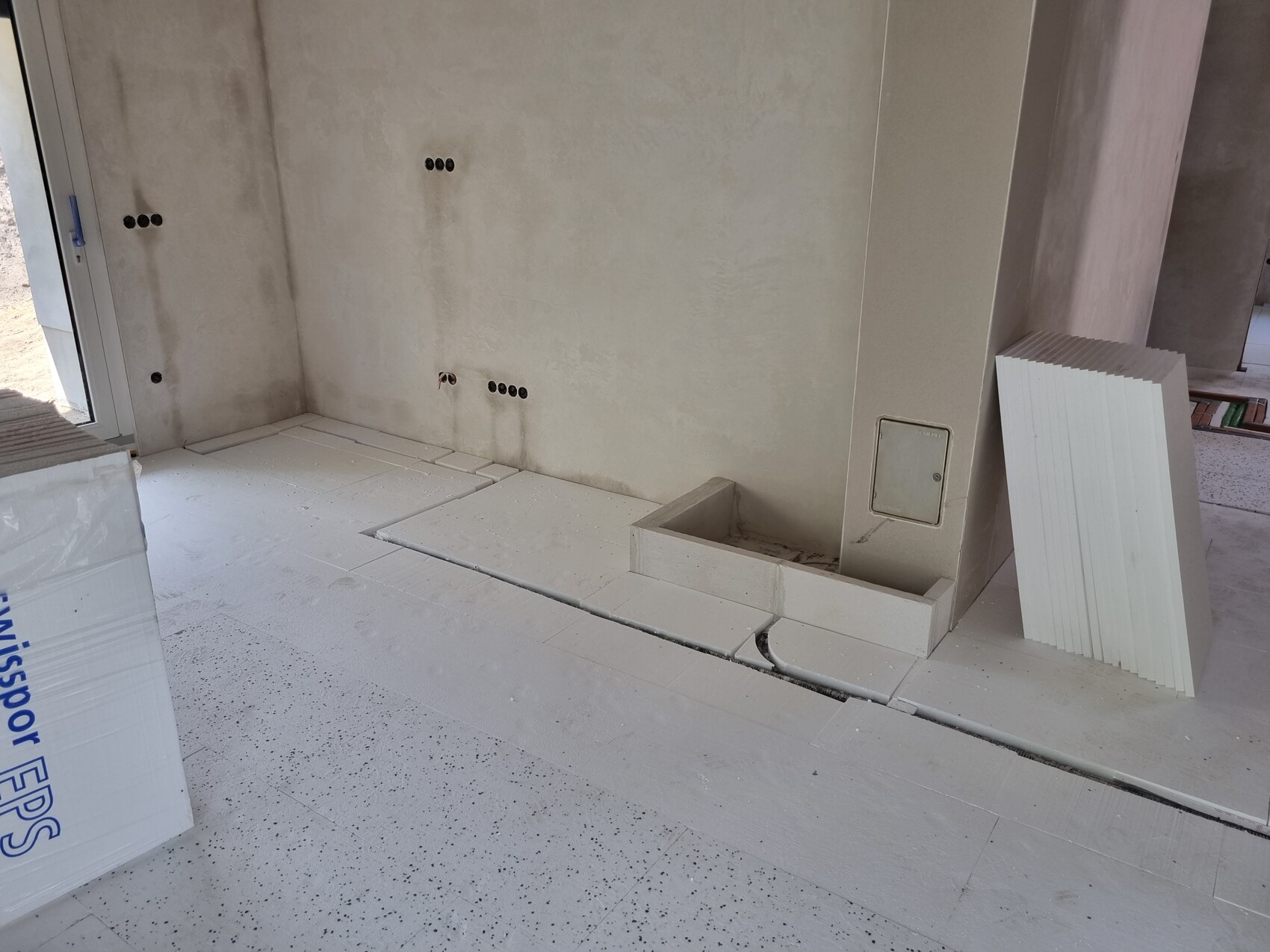Unverputzte Baustelle: Wand mit runden Steckdosenlöchern, Bodenplatten und Paneele