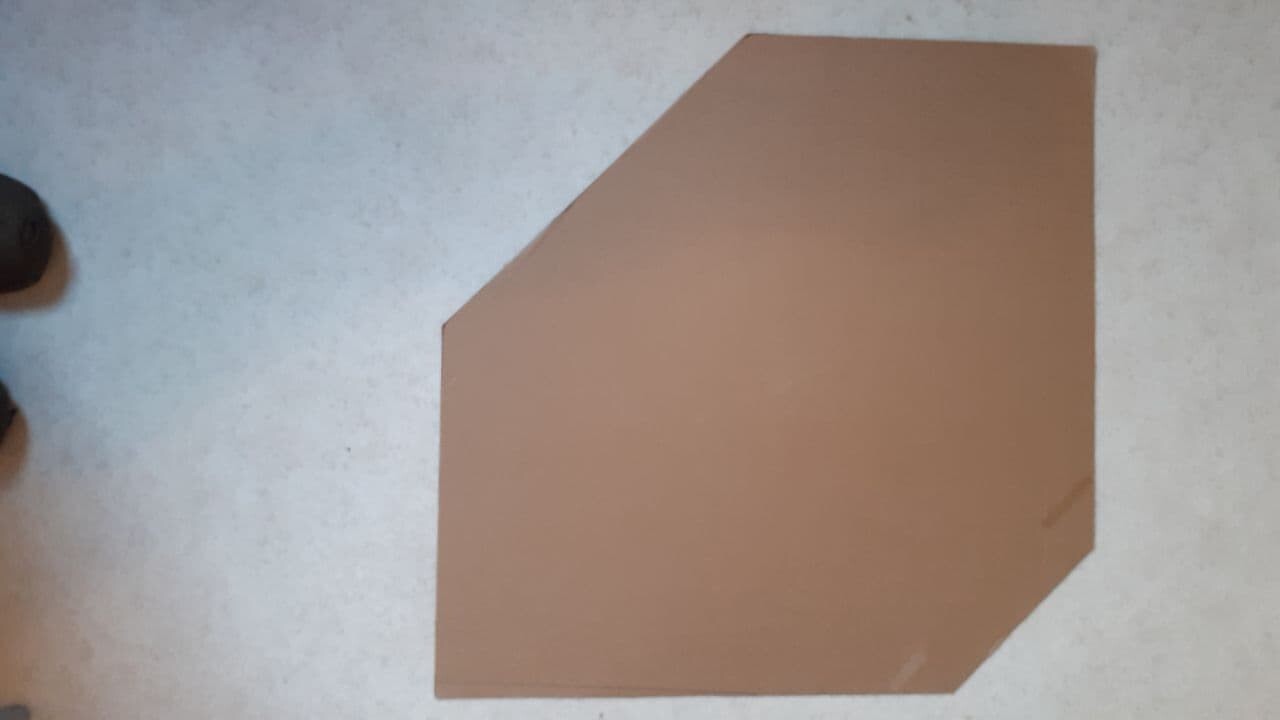 Unregelmaessiges braunes Kartonstueck liegt auf hellem Boden