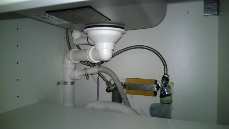 Unter dem Spülbecken sichtbare Installationsrohre und Verschraubungen