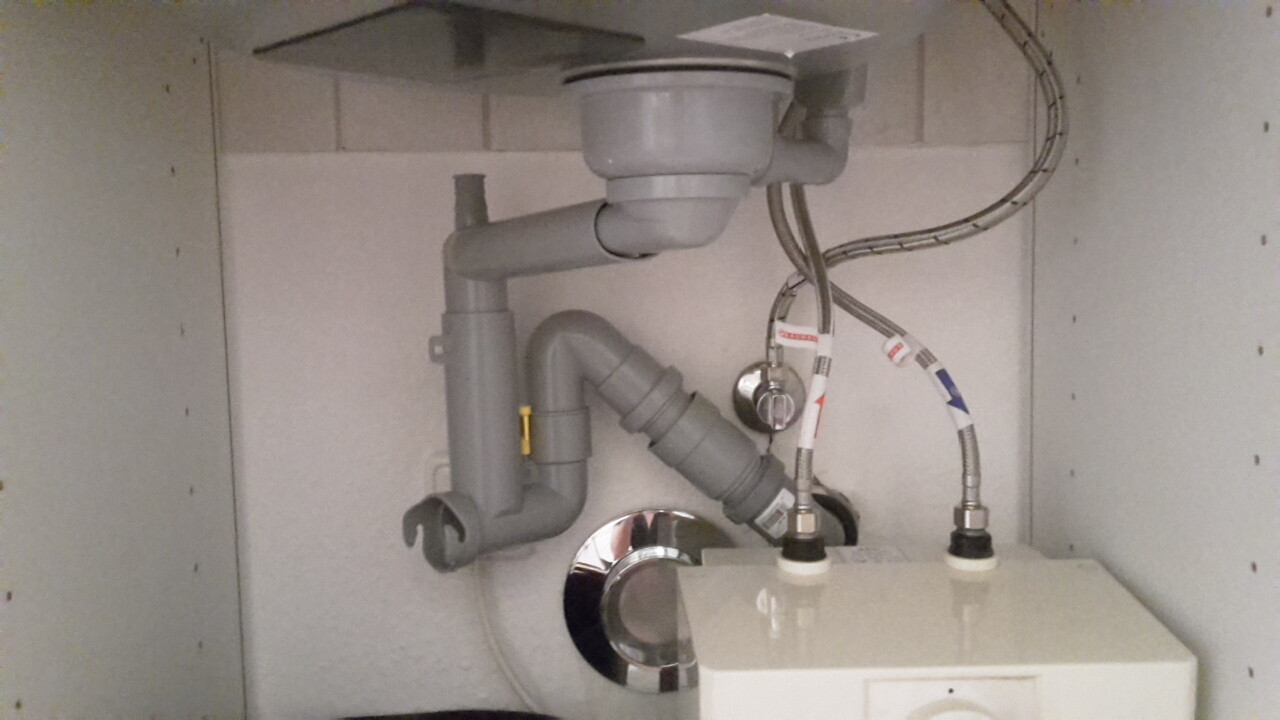 Unter dem Spülbecken: Siphon, Abflussrohr, Rohrverbindungen und Wasserleitungen.