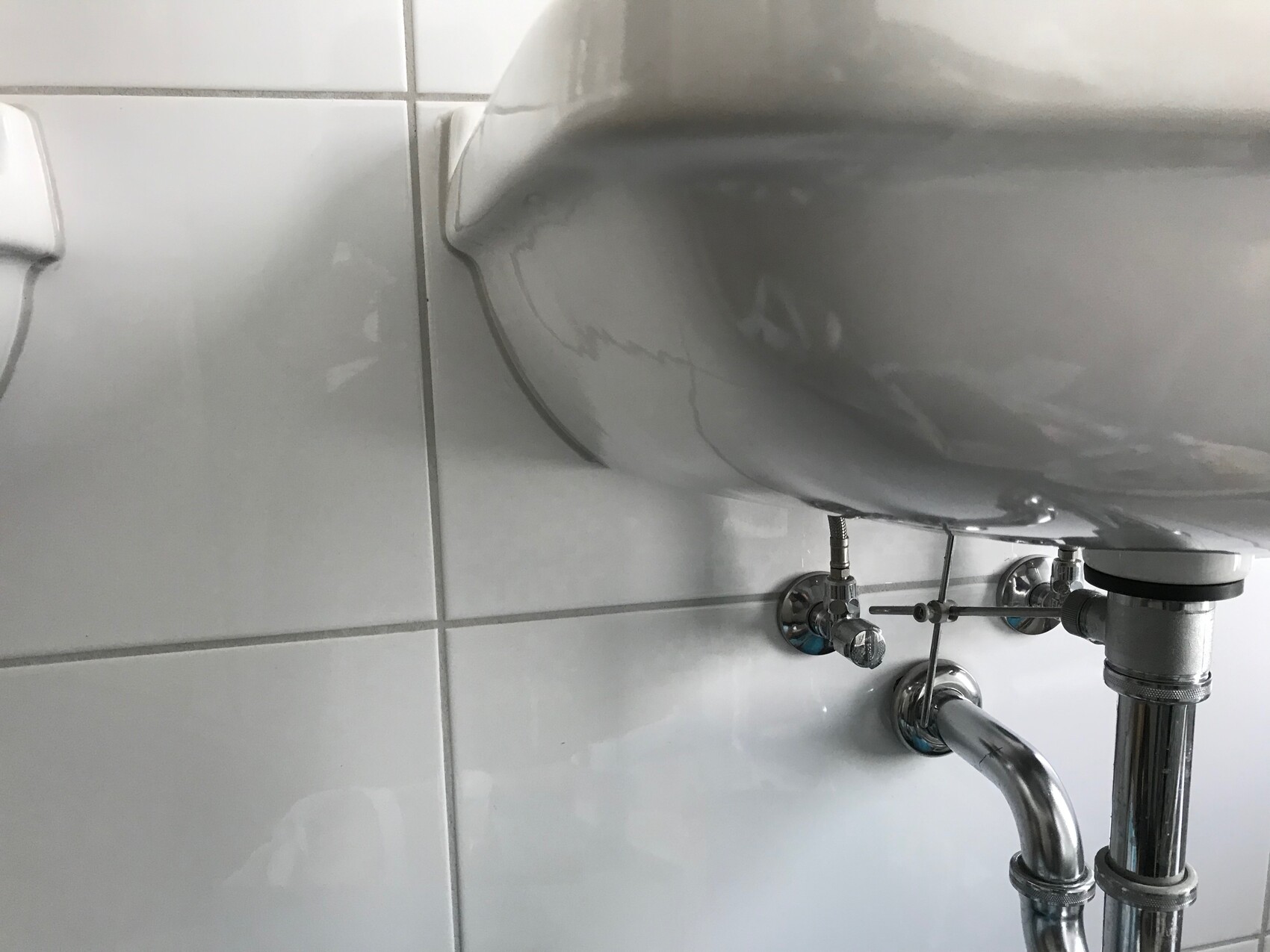 Unter dem Waschbecken sichtbare Sanitärrohre und Abflussrohre im Badezimmer