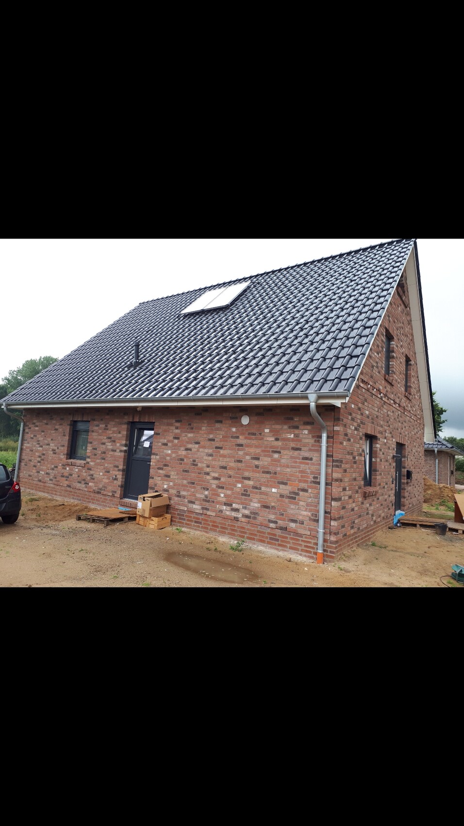 Neues Ziegelhaus mit Satteldach, Dachfenster und Baustelle im Vorgarten.