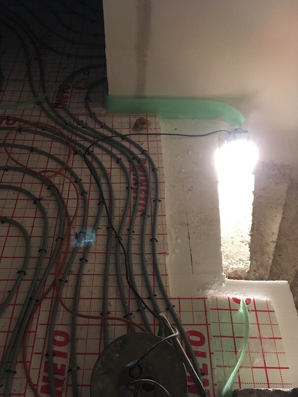 Baustelle: Viele Kabel liegen kreuz und quer auf rotem Rasterboden, grün markierte Kante, Licht.