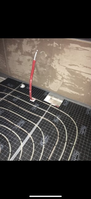 Installierte Unterbodenheizung mit Heizmatten und Rohleitungen im Rohbauboden.