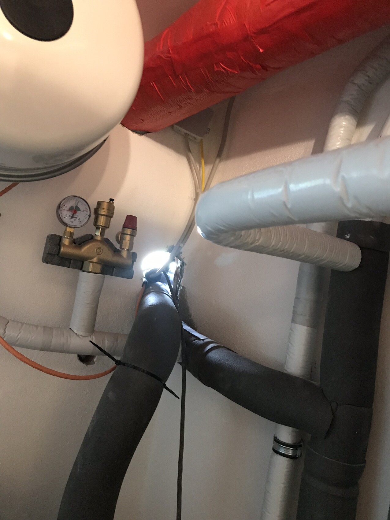 Rohrleitungsanlage mit Messingventil, Manometer und isolierten Rohren.