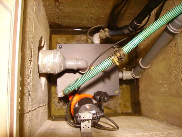 Kellerraum mit Haustechnik-Pumpe, Rohren und flexiblen Schläuchen