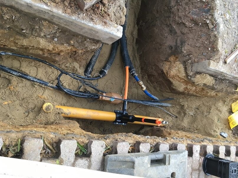 Ausgehobene Baugrube mit Rohren und Kabeln für Haustechnik im Erdreich