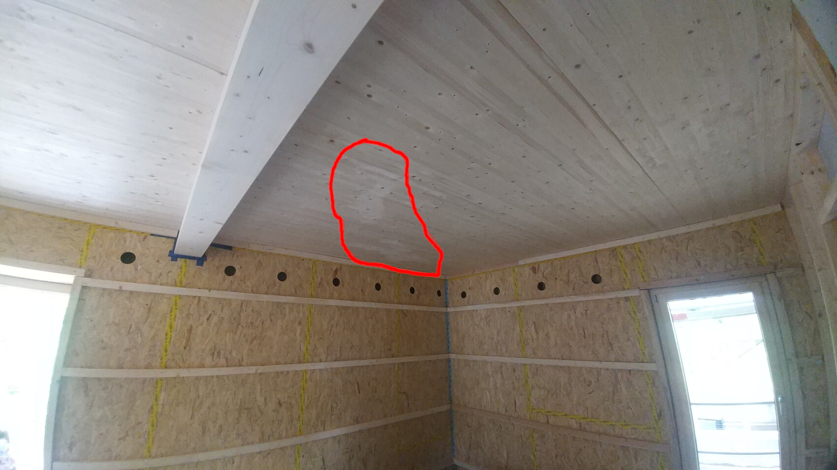 Unverkleideter Innenraum eines Bauprojekts: OSB-Wände, Holzbalkendecke, roter Umriss auf Decke