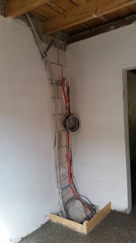 Rohbaustelle mit offenen Kabeln und Installationsleitungen an Innenwand und Decke