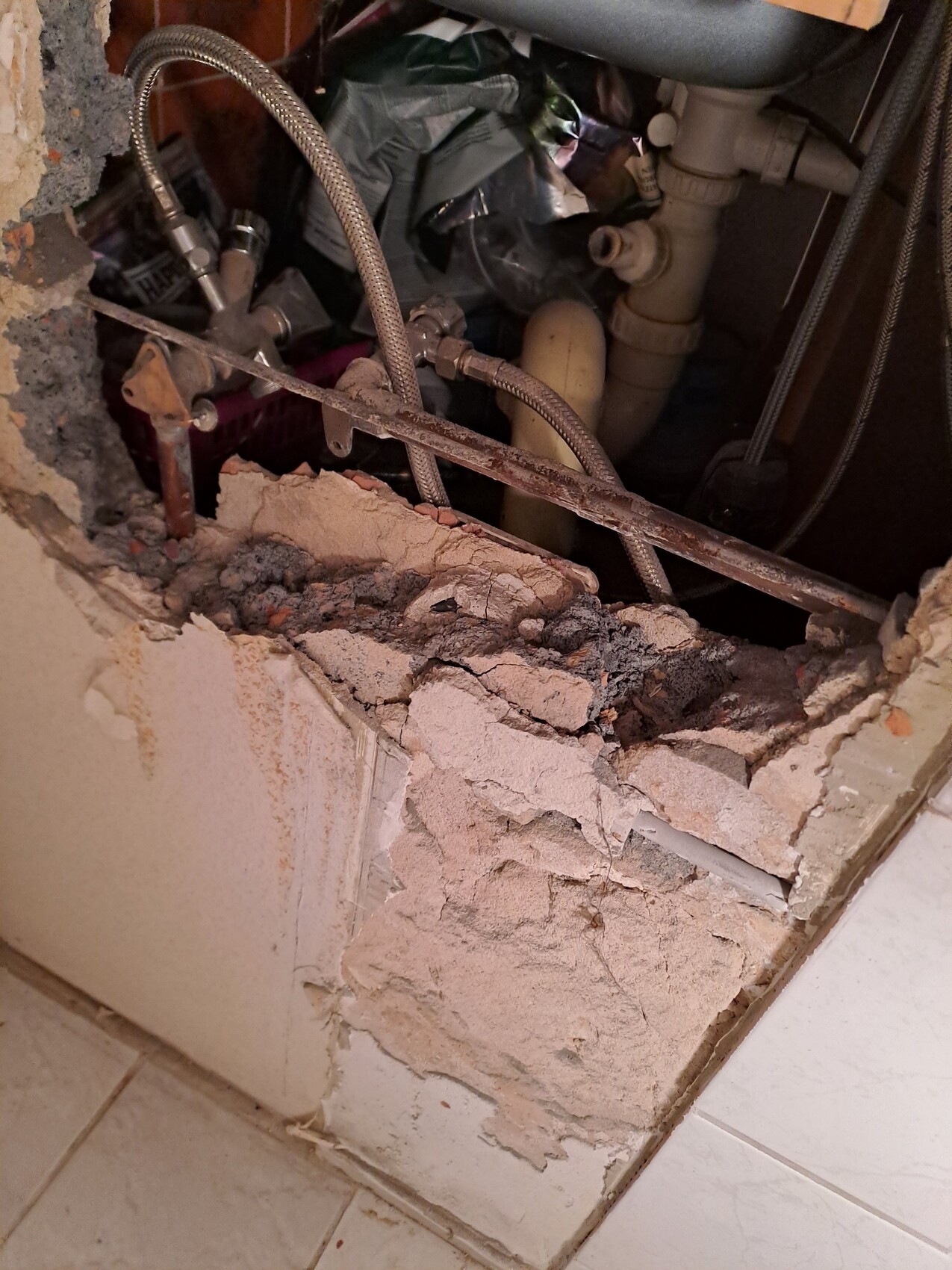 Offene Rohrleitungen hinter beschädigter Wand im Badezimmer