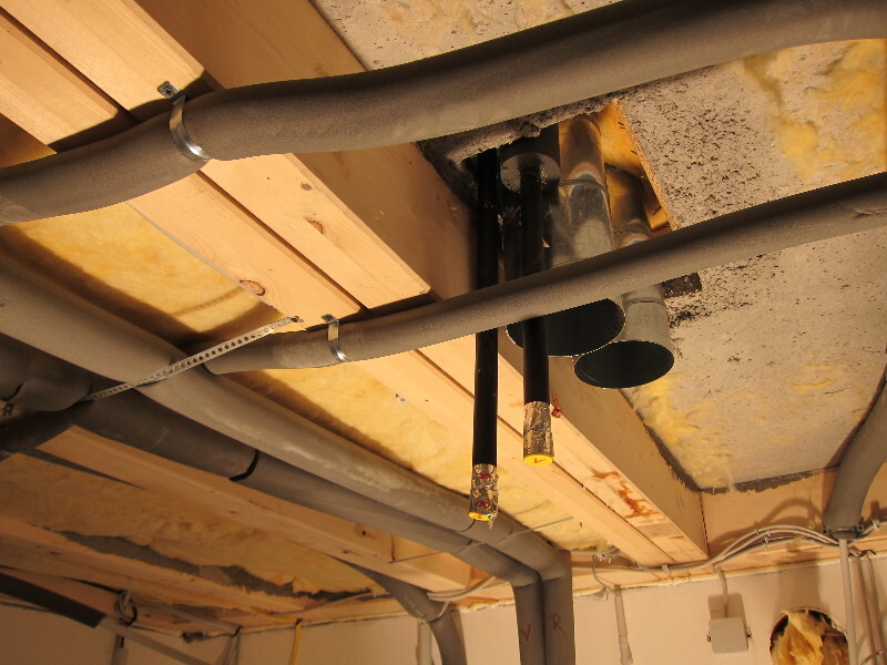 Sichtbare Rohre, Kabel und Dämmung an einer Decke auf einer Baustelle
