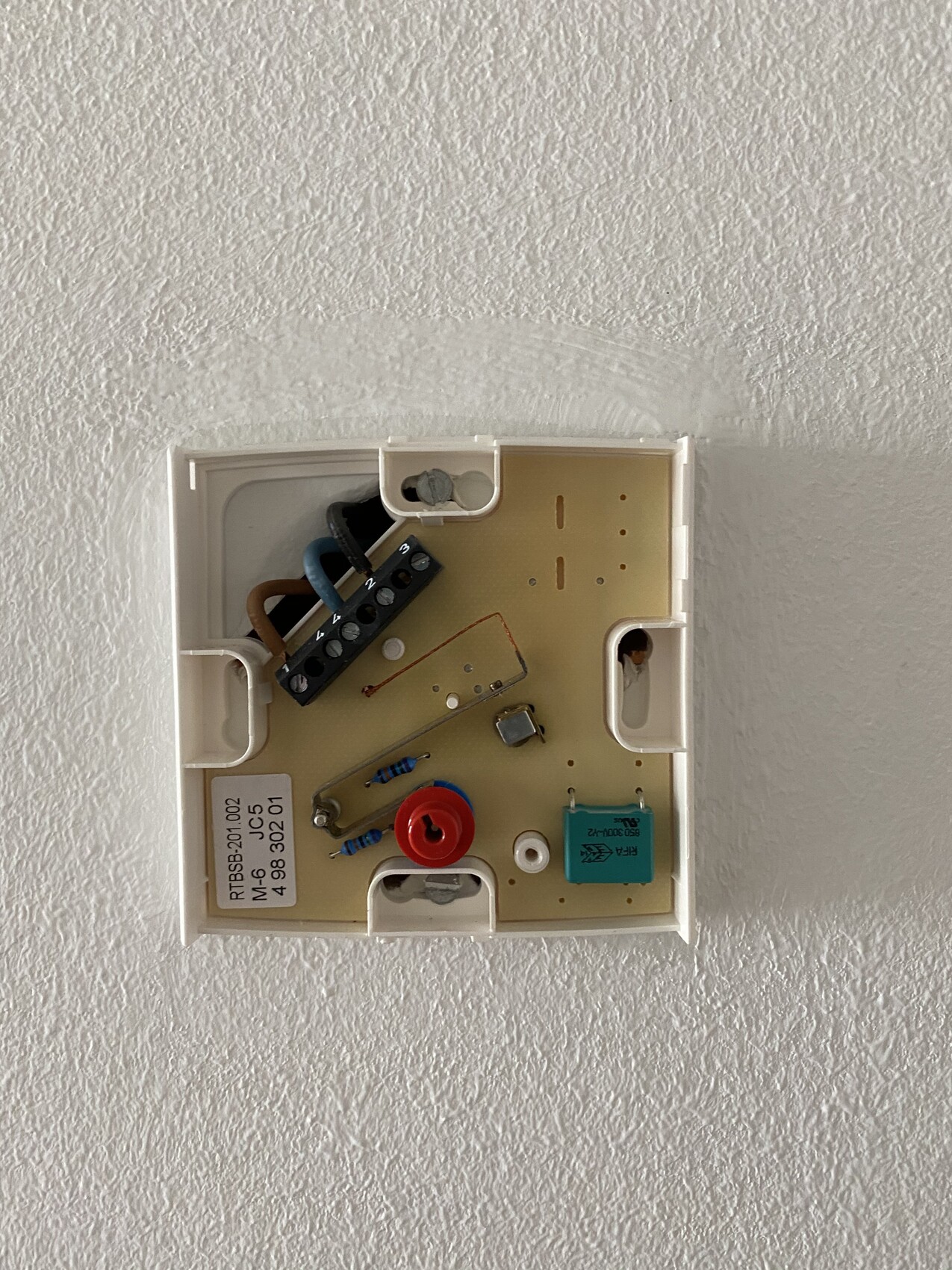 Innenansicht eines Wandthermostats mit Platine, Kabeln, Widerständen und Knopf