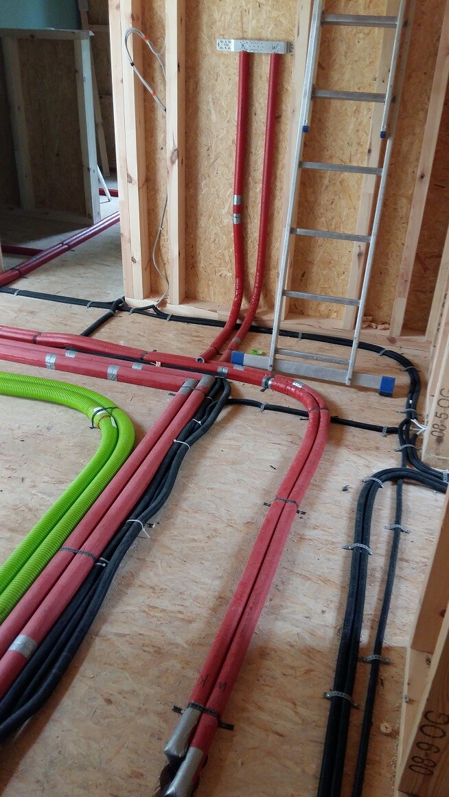 Verlegte rote und schwarze Kabel, grüne Leitung, Leiter im Rohbau.
