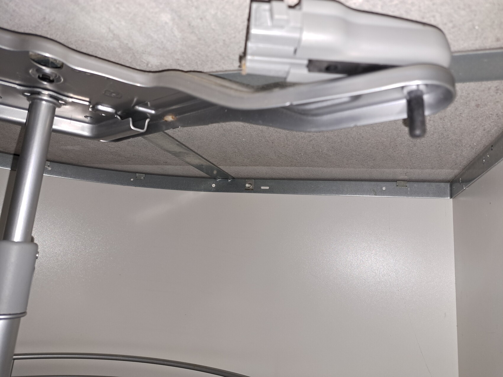 Unterseite eines Metallrahmens mit Hebelmechanismus und grauem Griff.