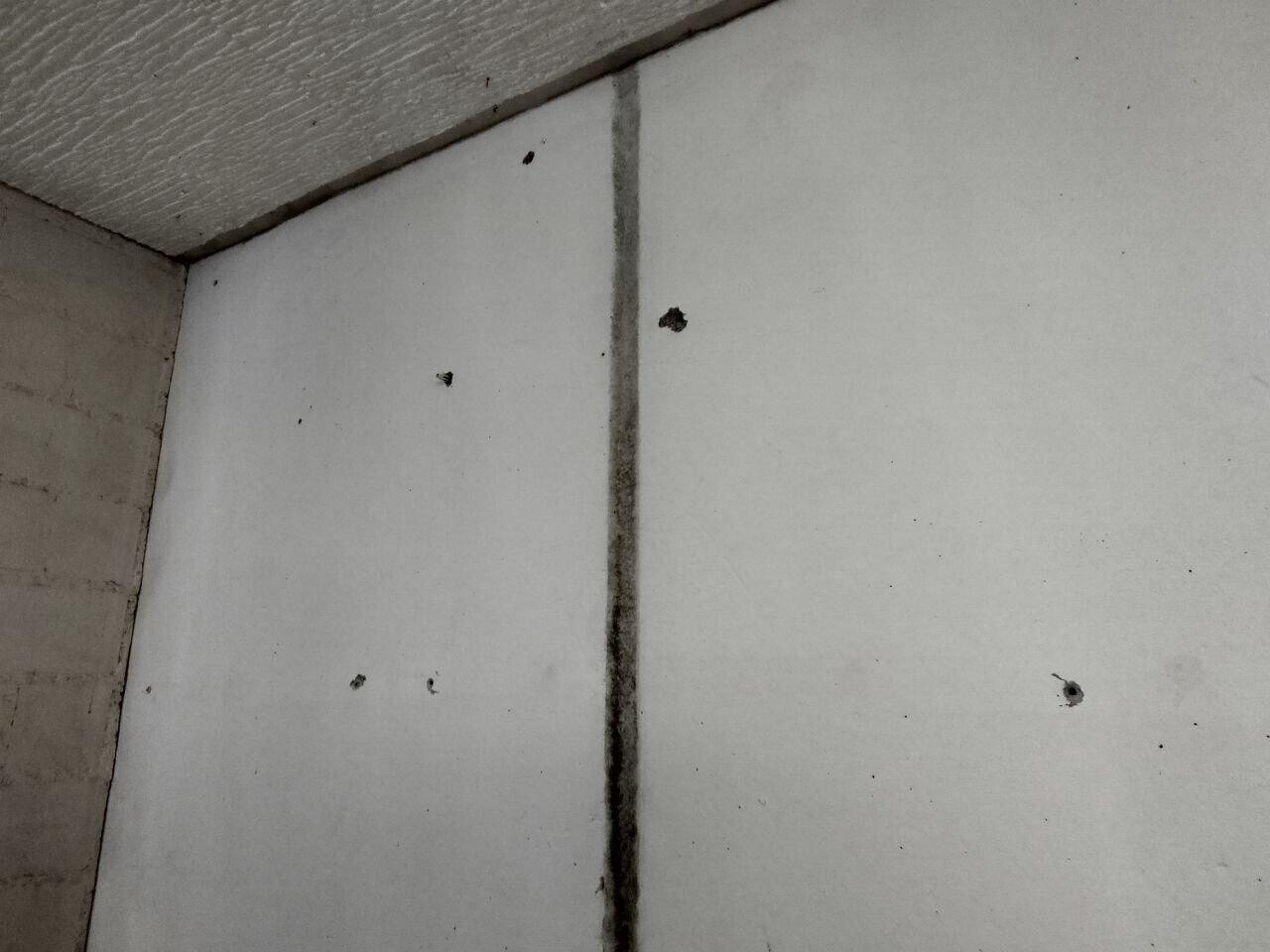 Weiße Wand-Ecke mit dunkler senkrechter Fuge und kleinen Flecken