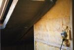 Unverputzte Innenwand im Baubereich mit sichtbarer Rohrinstallation in einer dunklen Ecke.