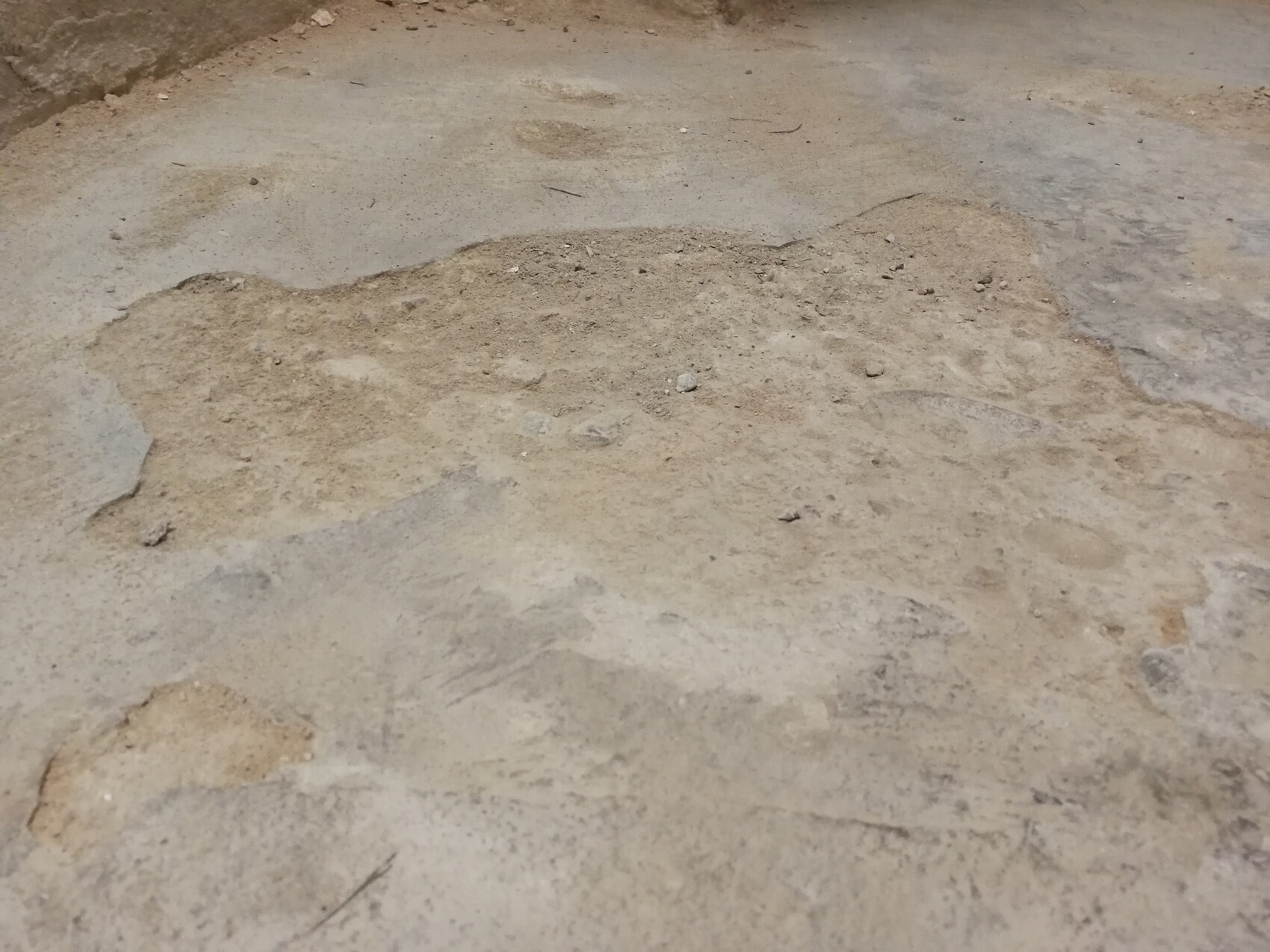 Betonboden mit unregelmäßigen Staub- und Schmutzflecken.