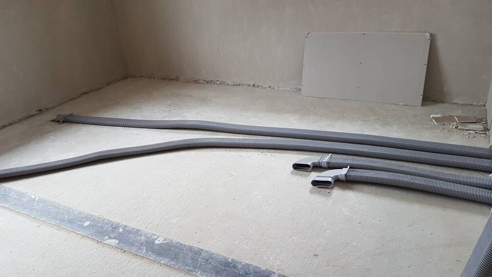 Unbearbeiteter Bauraum mit flexiblen Kabelschläuchen auf dem Boden.