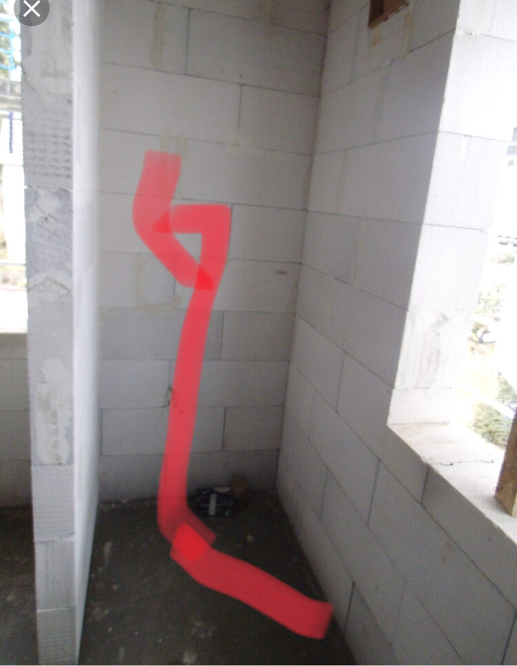 Rohbau-Ecke mit grauen Betonblöcken; roter, abstrakter Sprühstrich an der Wand.