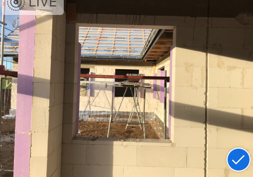 Innenansicht eines Rohbaus mit Fensteröffnung, Gerüst und Holzdach.