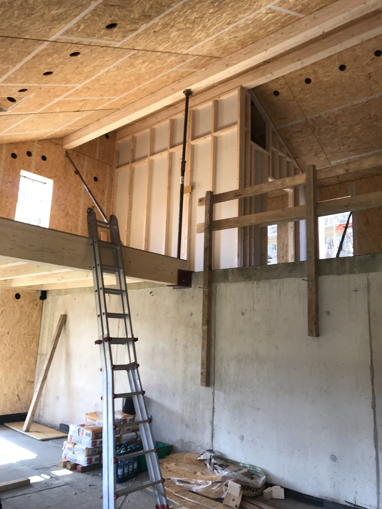 Innenraum einer Baustelle mit Holzrahmen, Leiter und Betonwand.