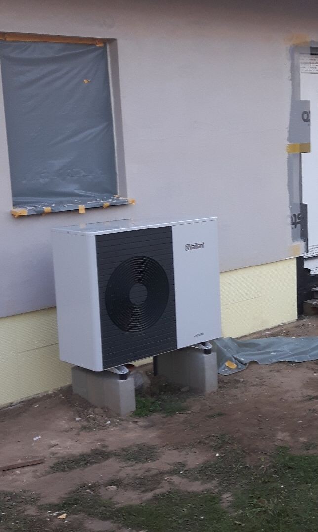 Vaillant Außen-Einheit für Heizung, vor Hauswand auf Betonsteinen, Fenster abgedeckt.