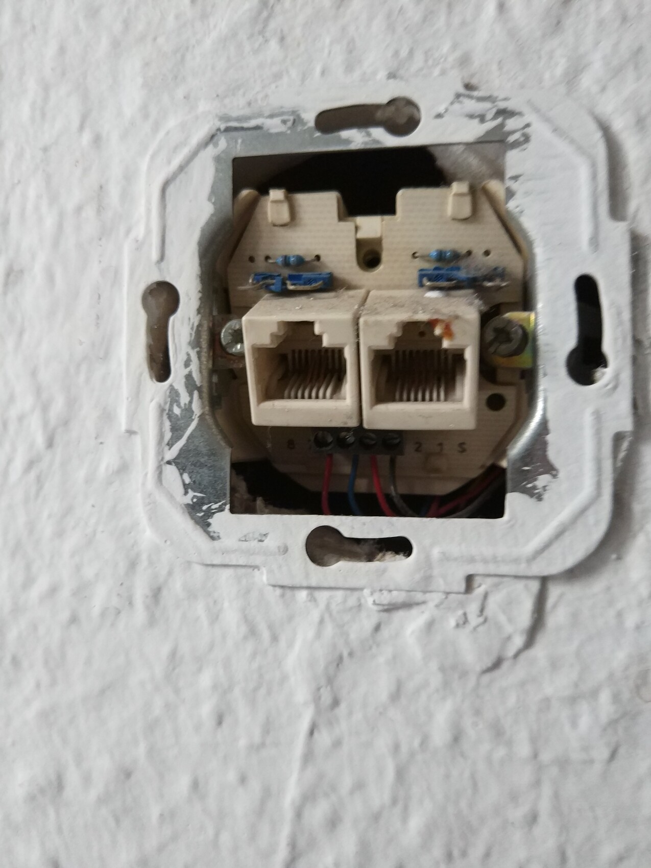 Wandmontiertes Doppel-Modul mit zwei offenen RJ-45/Telefonbuchsen, sichtbare Kabel.