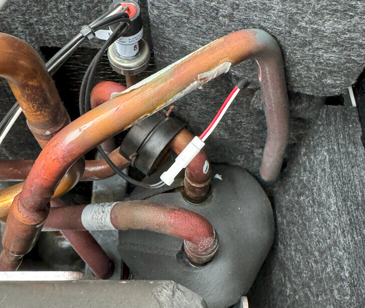 Nahaufnahme von Kupferrohren, Sensor und Kabeln in einer Klimaanlagen- oder Heizungsanlage.
