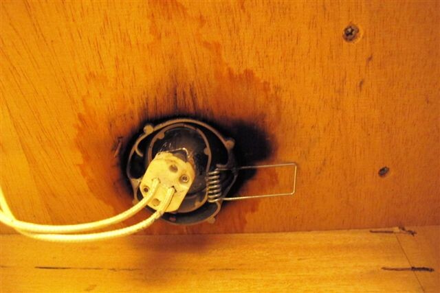 Verbrannte Öffnung um Steckdose in Holzwand, elektrischer Defekt sichtbar
