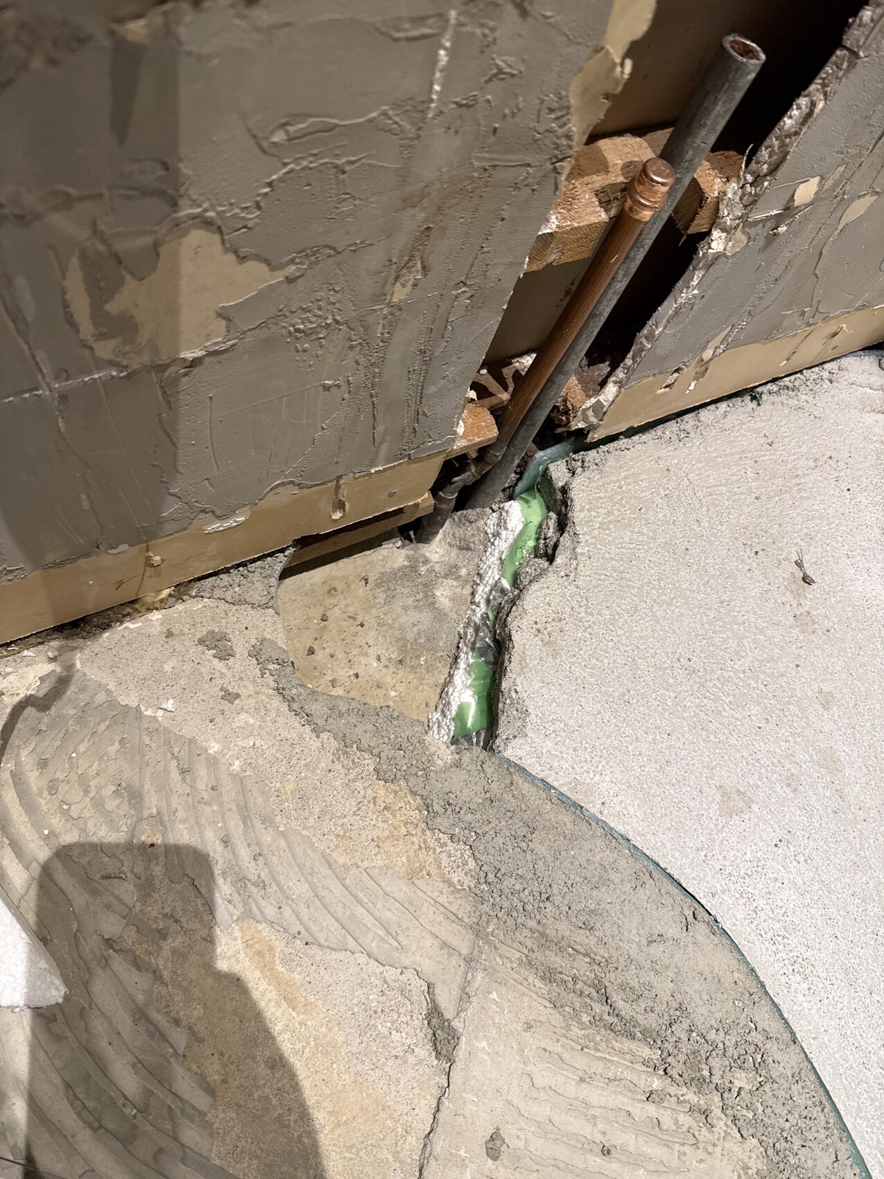 Freigelegte Kupferrohre in beschädigter Wand auf einer Baustelle