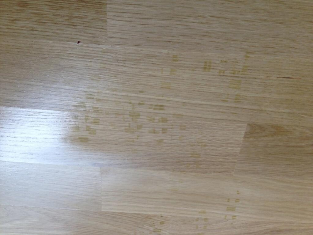 Holzboden mit verstreuten gelben quadratischen Flecken auf der Oberfläche.