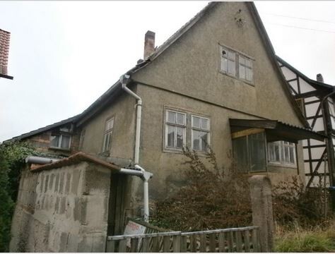 Verfallenes Haus von außen mit Dach, Fenstern und überwucherter Vegetation