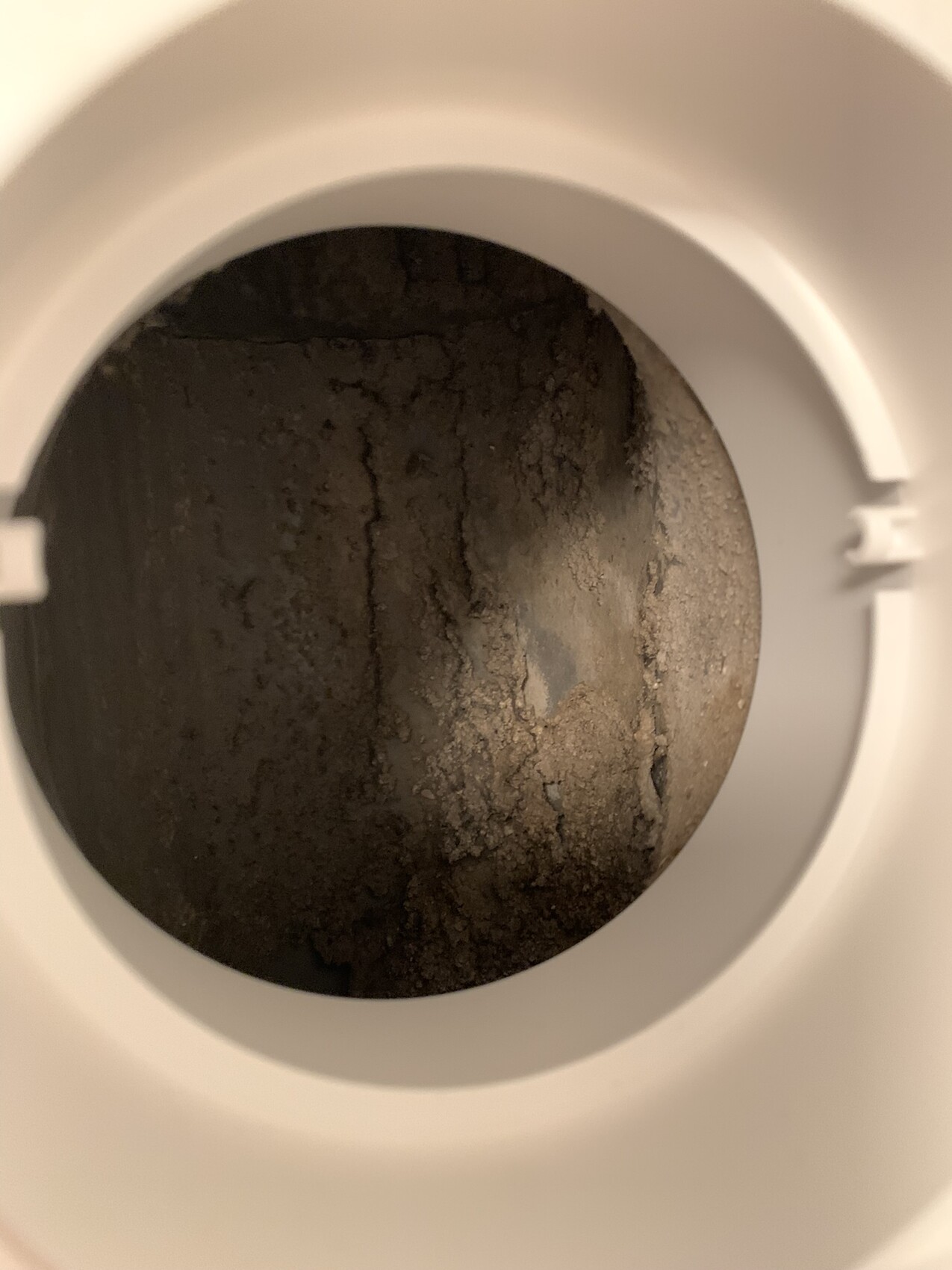 Blick in eine Toilette: runde Öffnung mit braunen, krustigen Ablagerungen am Innenboden.