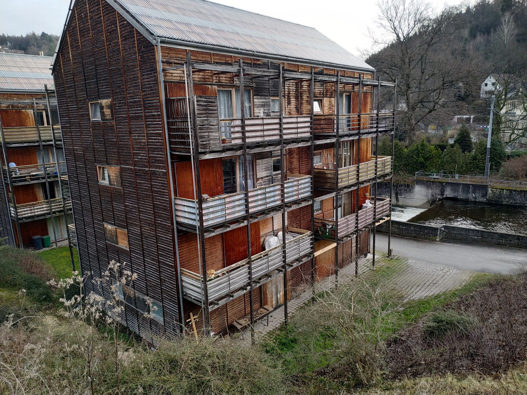 Vierstöckiges Holzwohnhaus mit Holzbalkonen aus Bretterlatten am Kanal.
