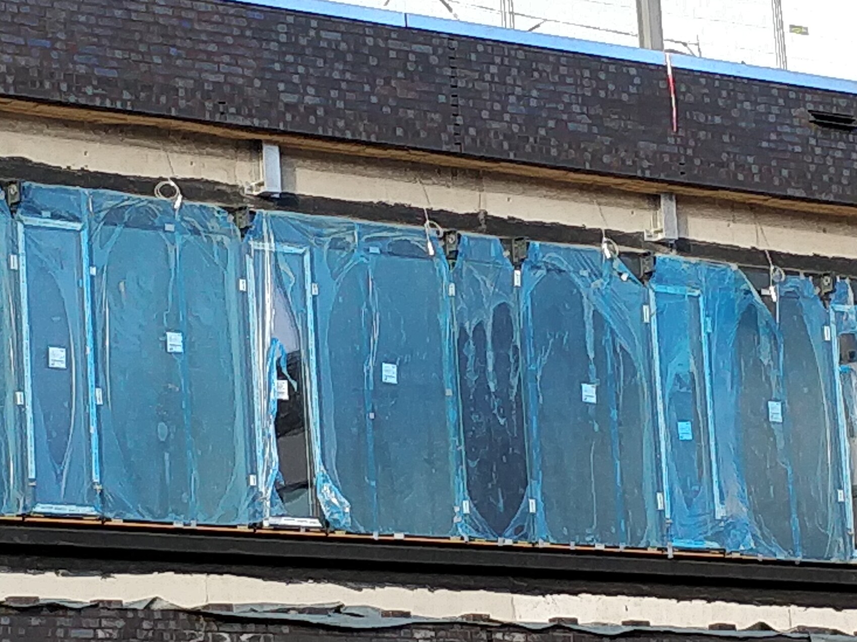 Reihe blauer Glasplatten in Schutzfolie an einer Fassadenbaustelle