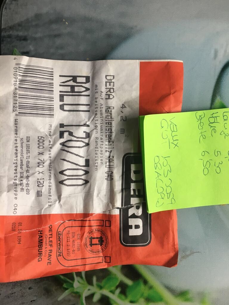 Nahaufnahme eines roten-orange Verpackungslabels mit Barcode und Notizzettel