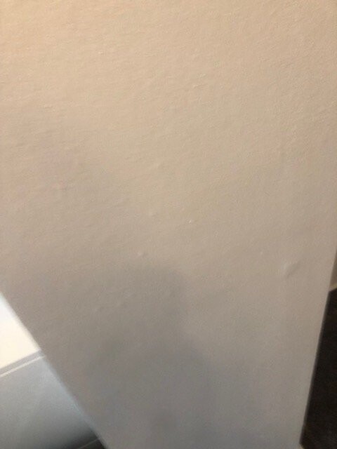 Nahaufnahme einer cremefarbenen Wand mit leichter Textur und dunkler Schattenkante unten