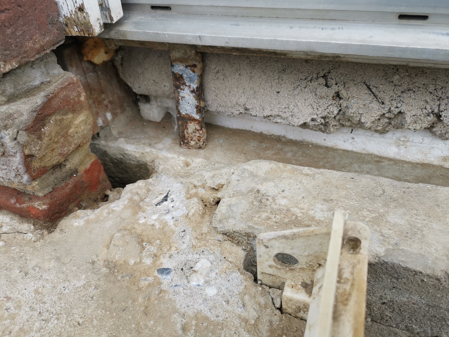 Beschädigte Außenwand mit Ziegel, Beton, rostenden Stahlträgern sowie Geröll und Mörtelresten.