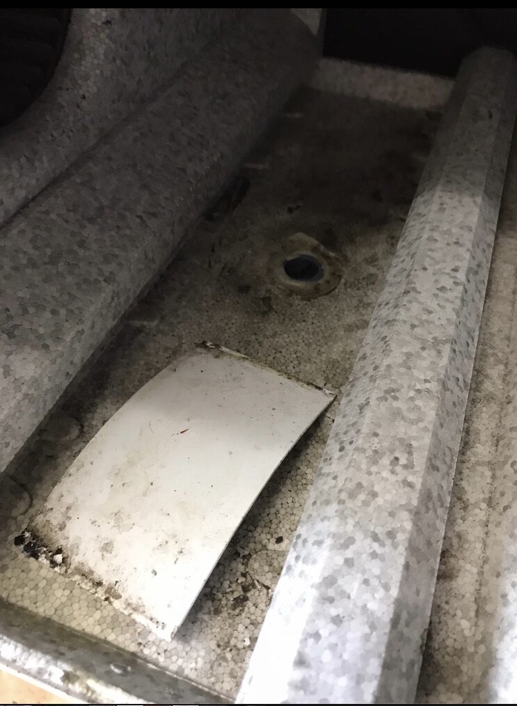 Innenansicht einer staubigen Metallwanne mit losem weißen Blechteil und Ablagerungen.