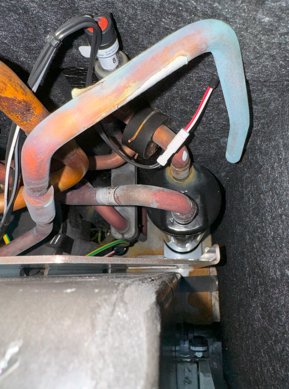 Innenansicht einer Heizungsanlage: Kupferrohre, Kabel, Schläuche und Ventil.