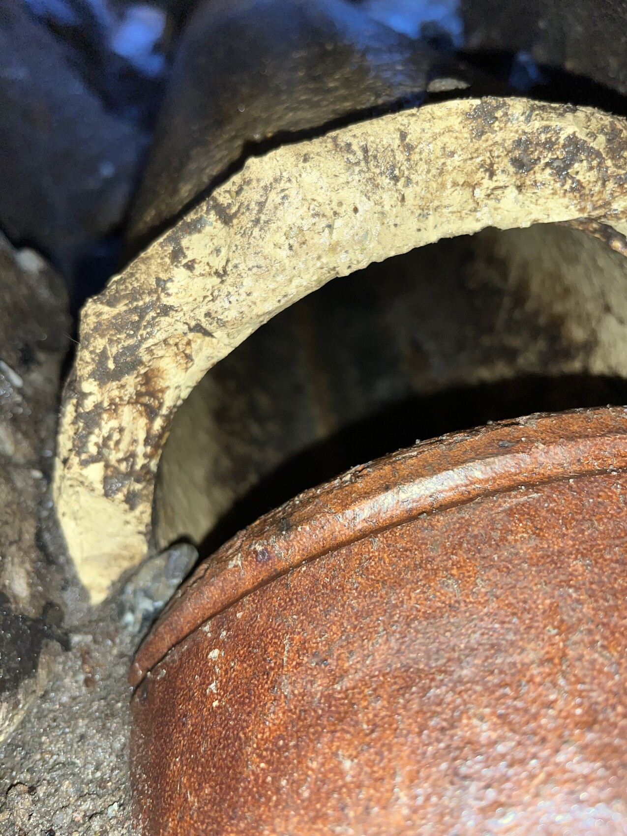 Nahaufnahme eines verschmutzten sandfarbenen Ringes neben rostigem Metallkörper.