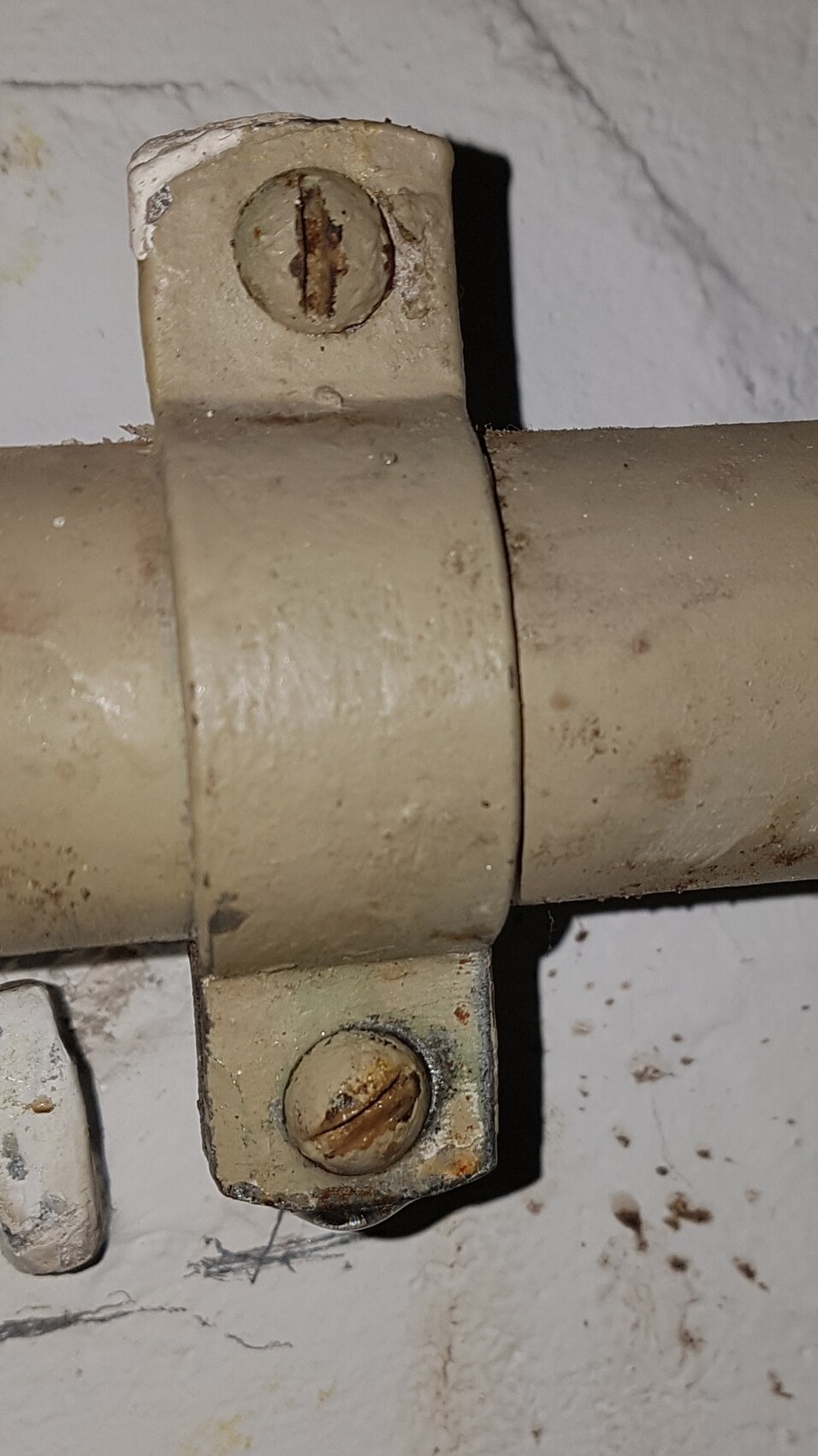 Nahaufnahme einer verrosteten Rohrverbindung mit Schraubklemmen an Heizungsleitung